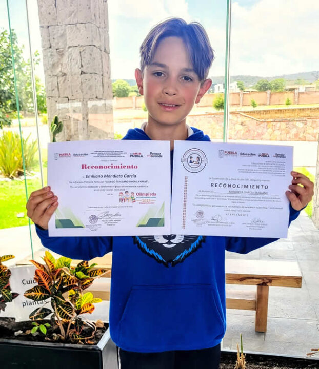 El ganador de zona de la Olimpiada del Conocimiento, mostrando sus diplomas